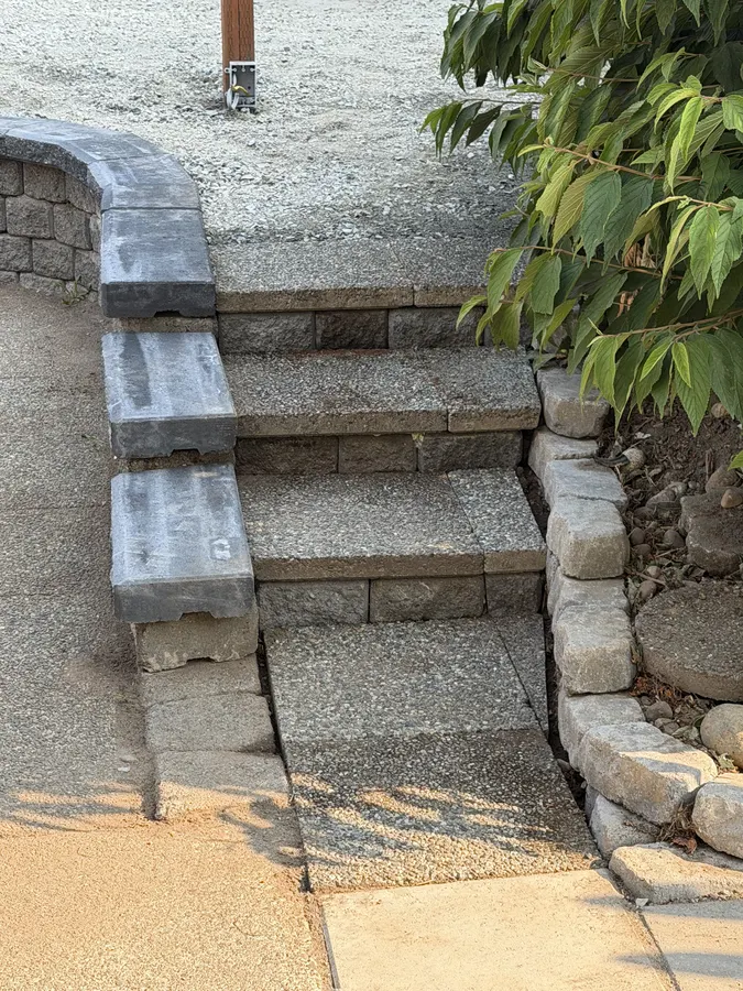 Finished paver patio with a capped retaining wall bordering the garden