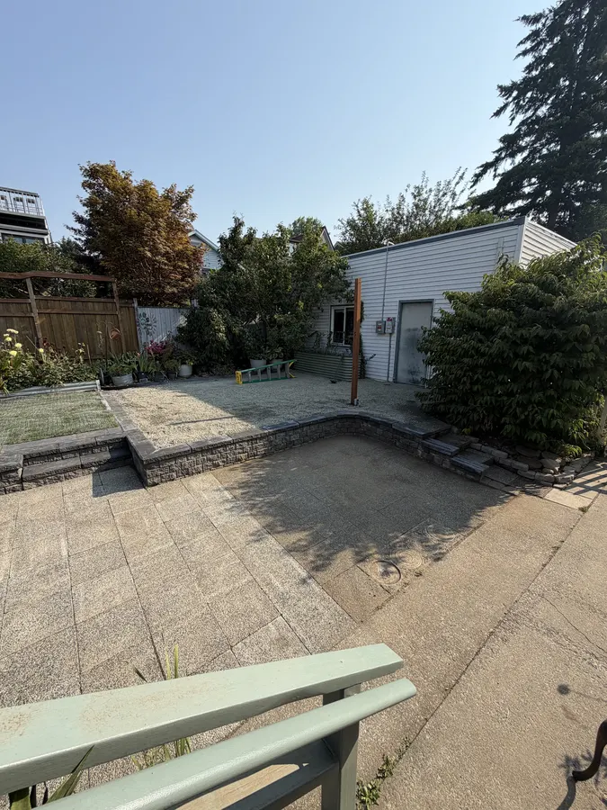 Finished paver patio with a curved retaining wall, steps, and raised gravel area